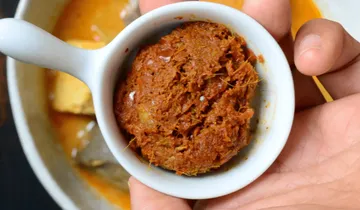Kleine Schüssel mit einer dicken, würzigen Paste in Hand.
