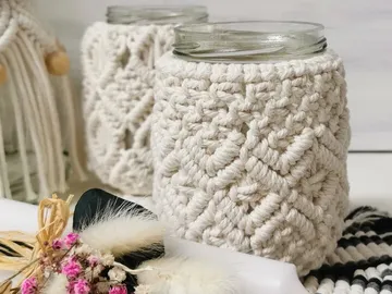 Glass container with macramé wrapping on a table.