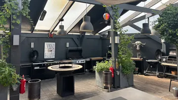Außenküche mit Grill unter einer Pergola.