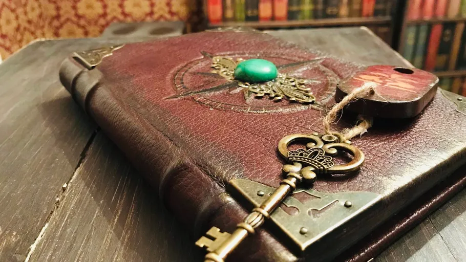 Altes Buch mit Schlüssel auf Holztisch.