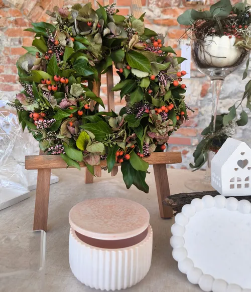 Floral wreath displayed on wooden easel indoors.