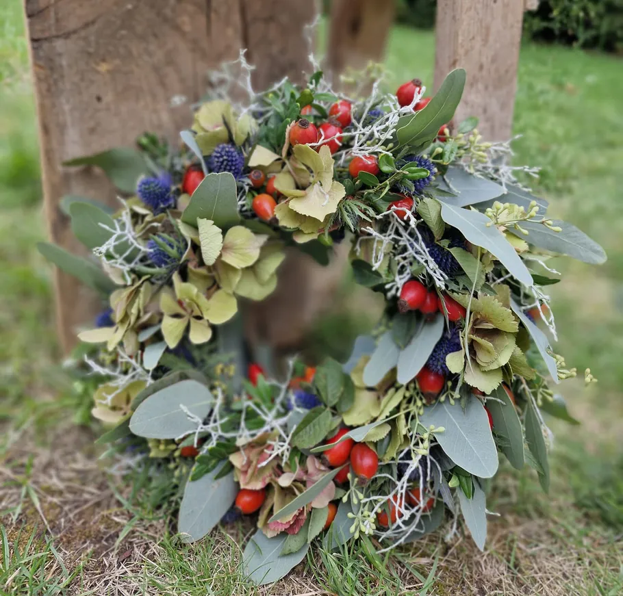 Floral wreath with berries on grass.