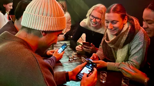 Freunde lachen zusammen, nutzen Handys in einer Bar.