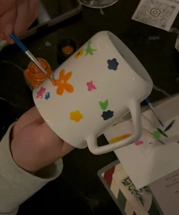Hand bemalt weiße Tasse mit bunten Blumen.