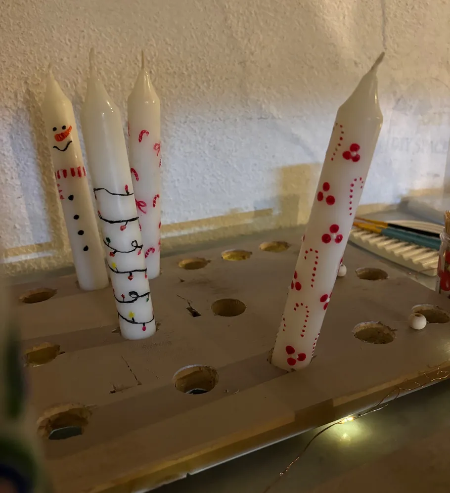 Decorated candles on a wooden holder indoors.