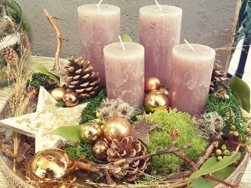 Kerzen stehen dekorativ in einem festlichen Arrangement mit Naturmaterialien.