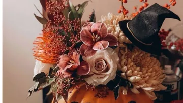 Floral arrangement in pumpkin with witch hat.