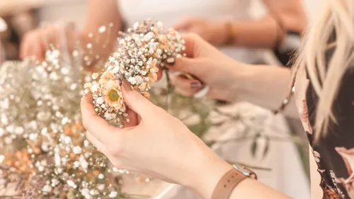 People arranging flowers delicately on table.