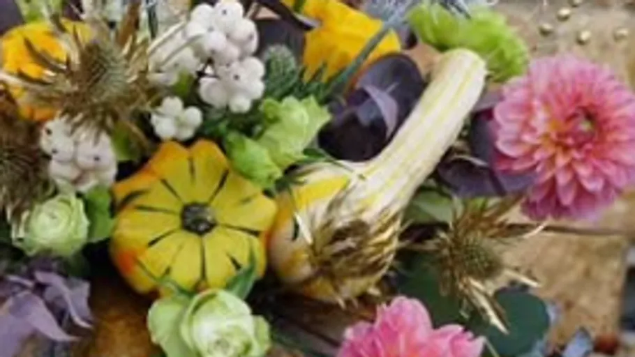 Verschiedene Kürbisse und Blumen im Strauß.