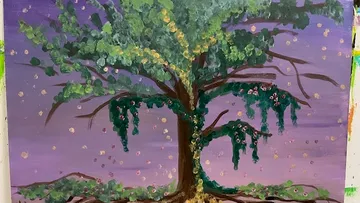 Baum mit bunten Blättern vor violettem Himmel.