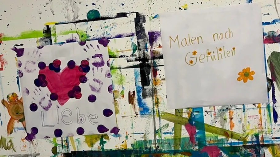 Zwei Gemälde mit Text auf bunter Wand.
