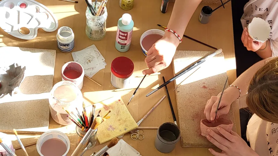 People painting ceramics on a table.