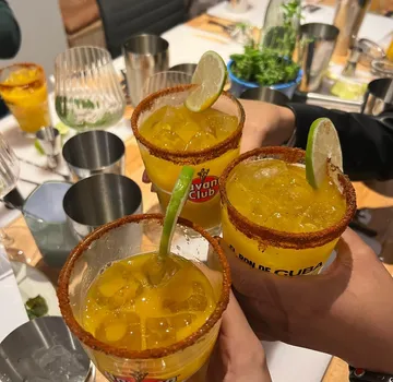 Three cocktails with lime garnish on table.