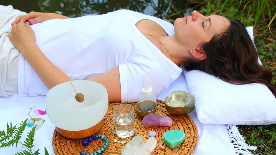 Person entspannt draußen mit Meditationsgegenständen.