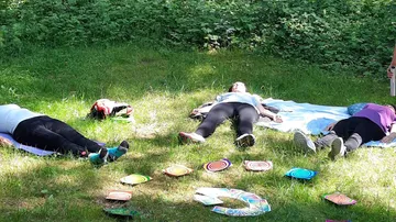 Drei Personen liegen auf Gras, bunte Scheiben herum.