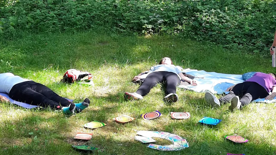 Three people lying on grass, colorful discs around.