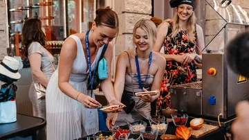 Women serving themselves food at buffet.