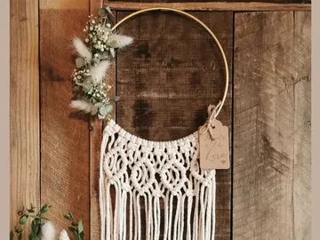Macrame hanging mold hangs on a wooden board with flowers