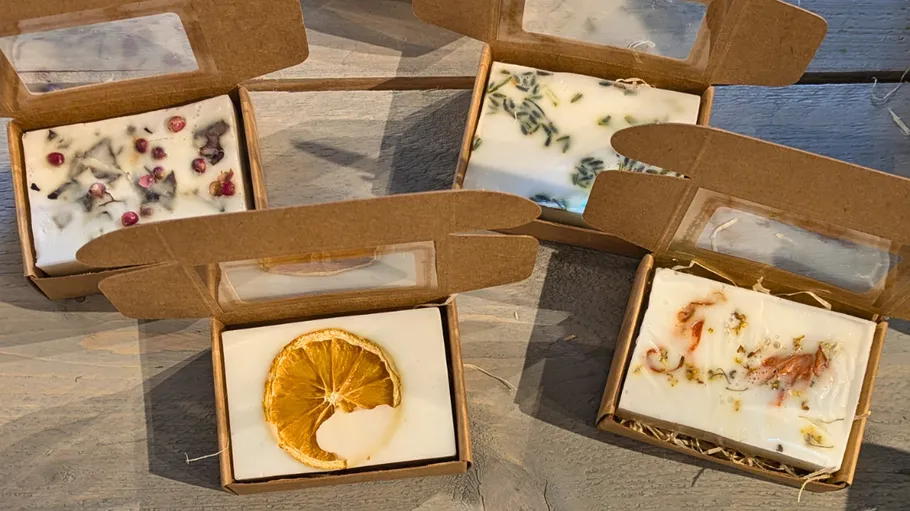 Four handmade soaps in open cardboard boxes.