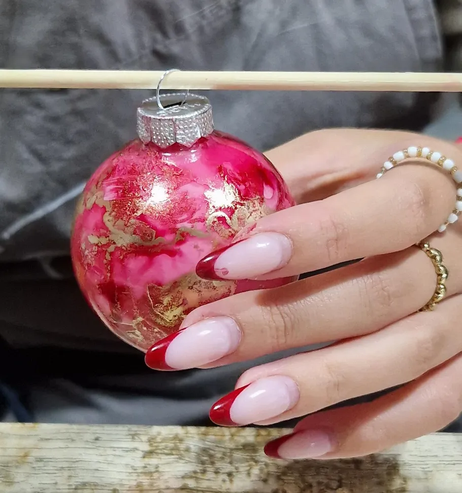 Hand holding pink ornament with nail art.