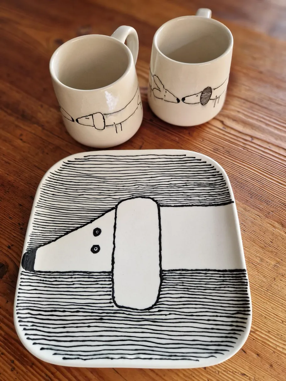 Ceramic mugs and plate with dog illustrations.