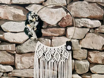 Macrame wall hanging in front of a stone wall.