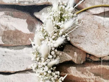 A beautiful white wreath hangs in front of a stone façade.