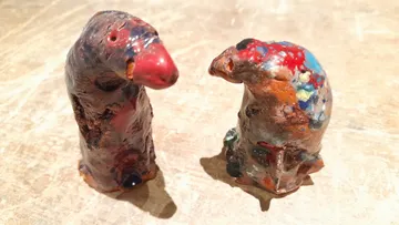 Zwei bunte Tonskulpturen auf Holzoberfläche.
