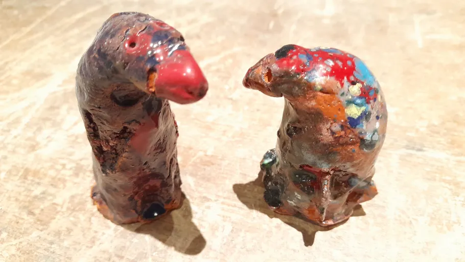 Two colorful clay sculptures on wooden surface.