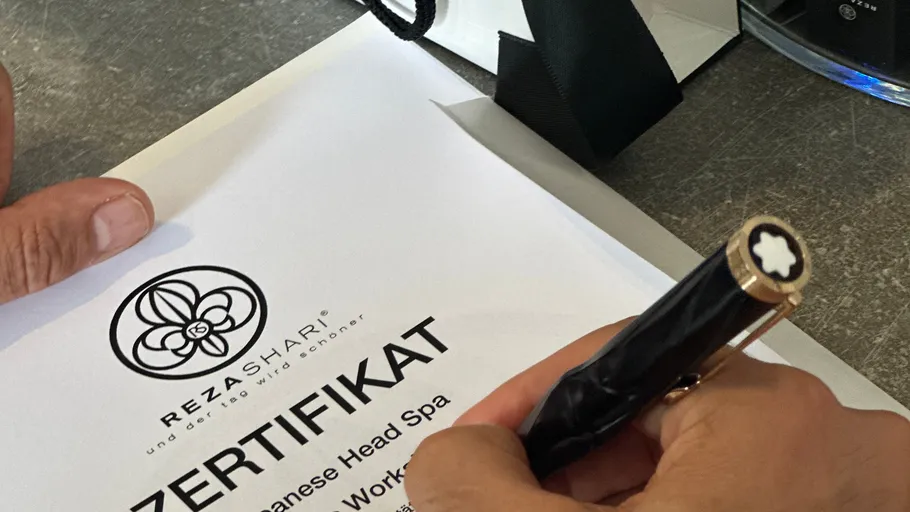 Person unterschreibt Zertifikat mit einem Stift.