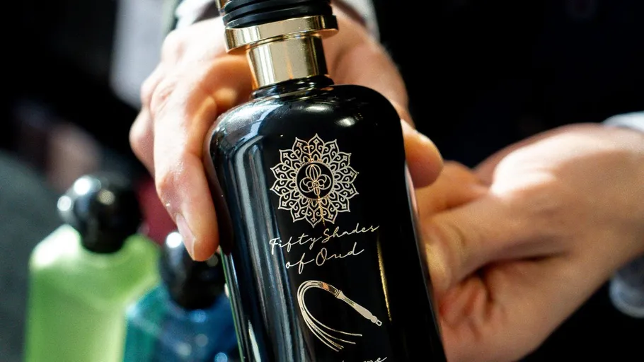 Hand hält dunkle Parfümflasche drinnen.