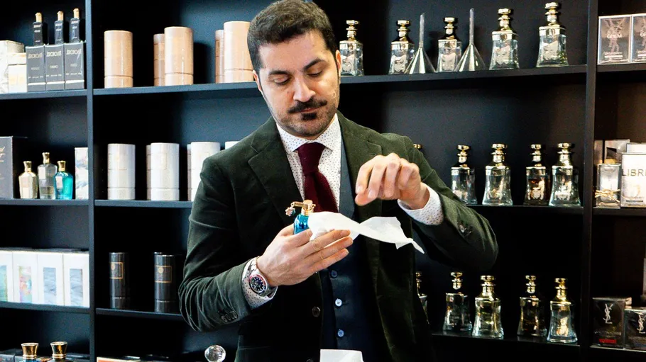 Man opening perfume bottle in store.