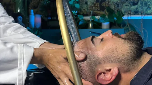 Friseur wäscht Haare eines Kunden im Salon.