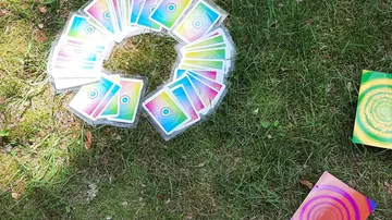 Colorful cards arranged in circular pattern on grass.