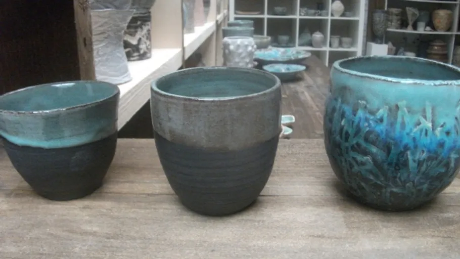 Three ceramic cups on wooden table.
