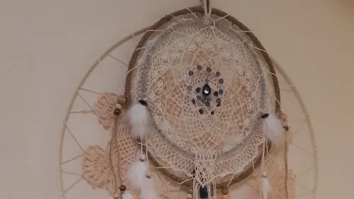 Dreamcatcher hanging on beige wall.