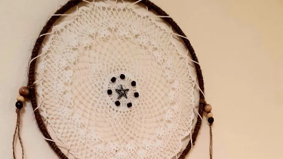 Dreamcatcher with lace pattern on wall.