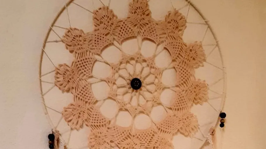 Crochet dreamcatcher with lace pattern on wall.