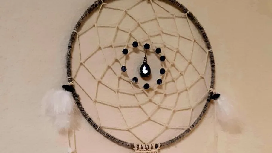 Dreamcatcher with feathers hangs on wall.