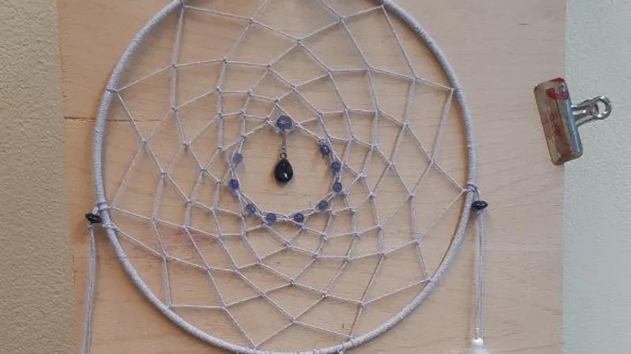 Dreamcatcher with beads on wooden background.