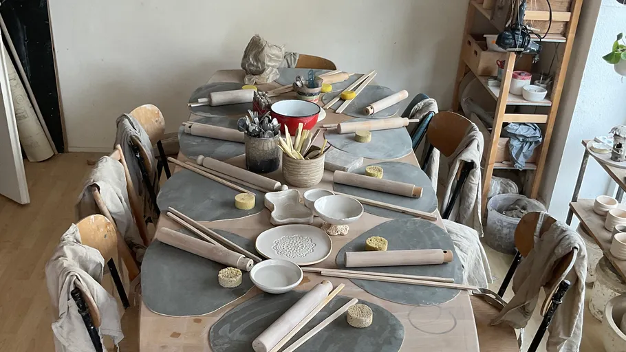 Table with pottery tools, bowls, and chairs.