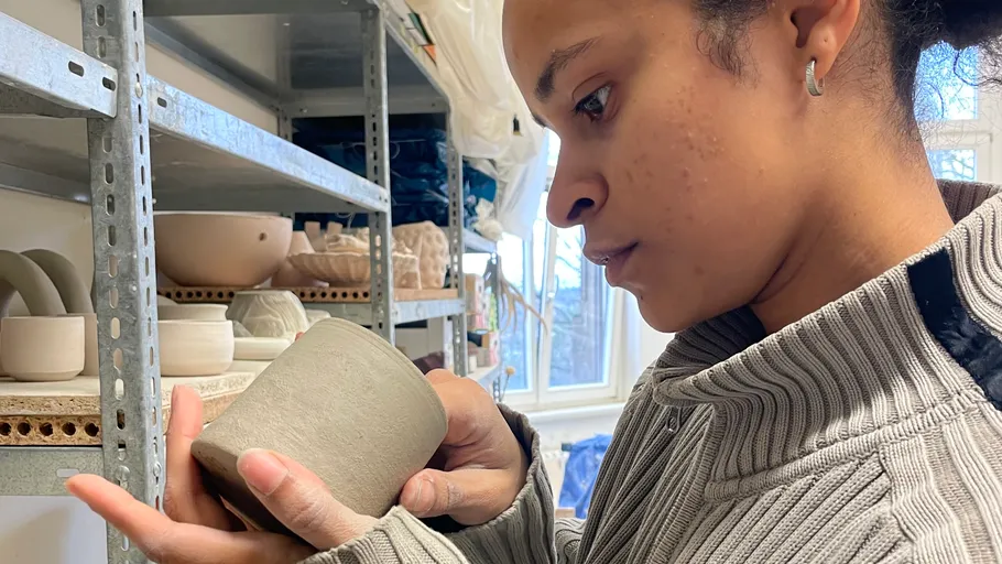 Person inspecting a clay cup in a studio.