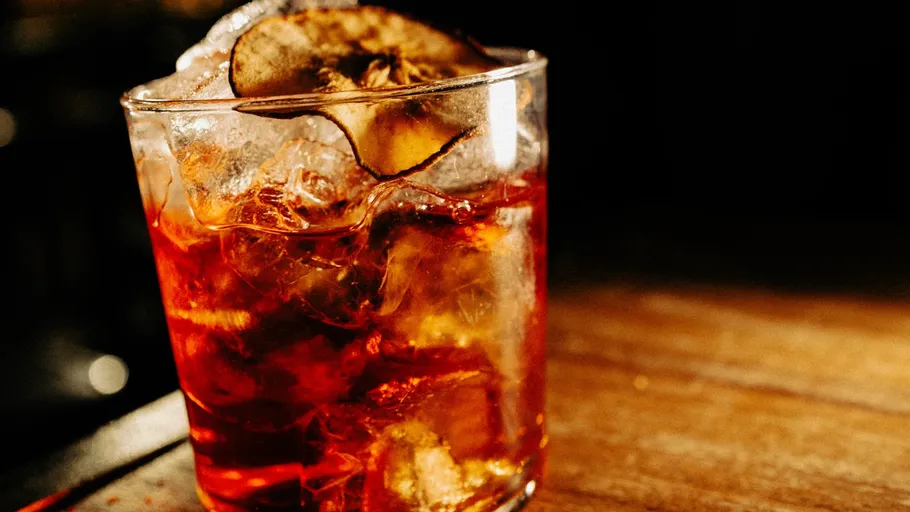 Cocktailglas mit Eis auf Holztisch.