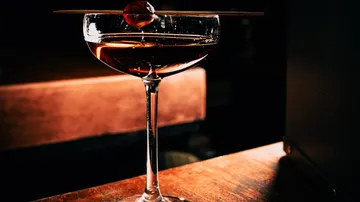 Cocktail glass with a cherry on a table.