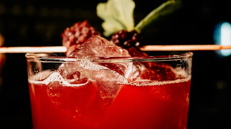Roter Cocktail mit Eis und Beerengarnitur.
