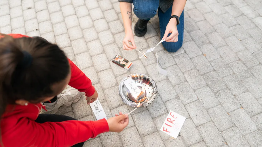 Two people burning paper outdoors.
