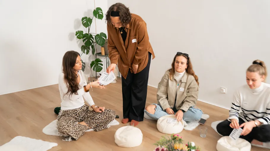 Vier Personen sitzen mit Papieren in einem Raum.