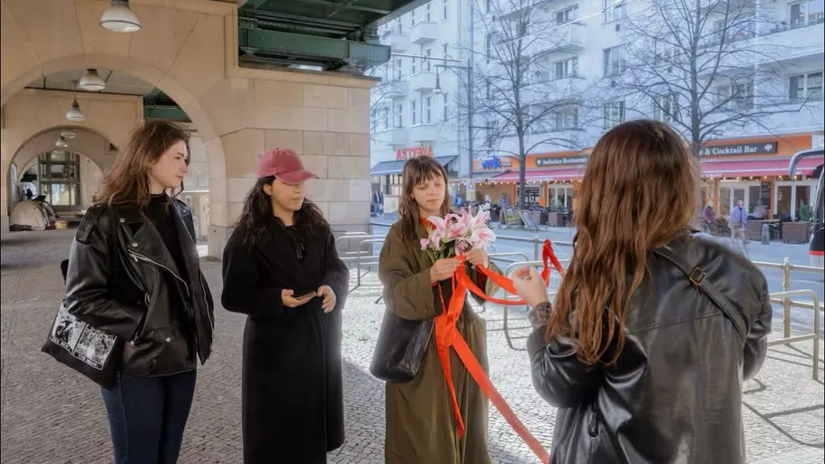 Vier Frauen stehen unter einer Überführung, mit Blumen.