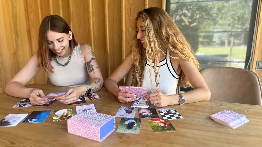 Zwei Frauen spielen ein Kartenspiel drinnen.