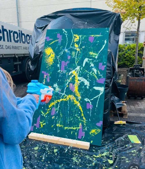 Person paints abstract art with toy water gun.